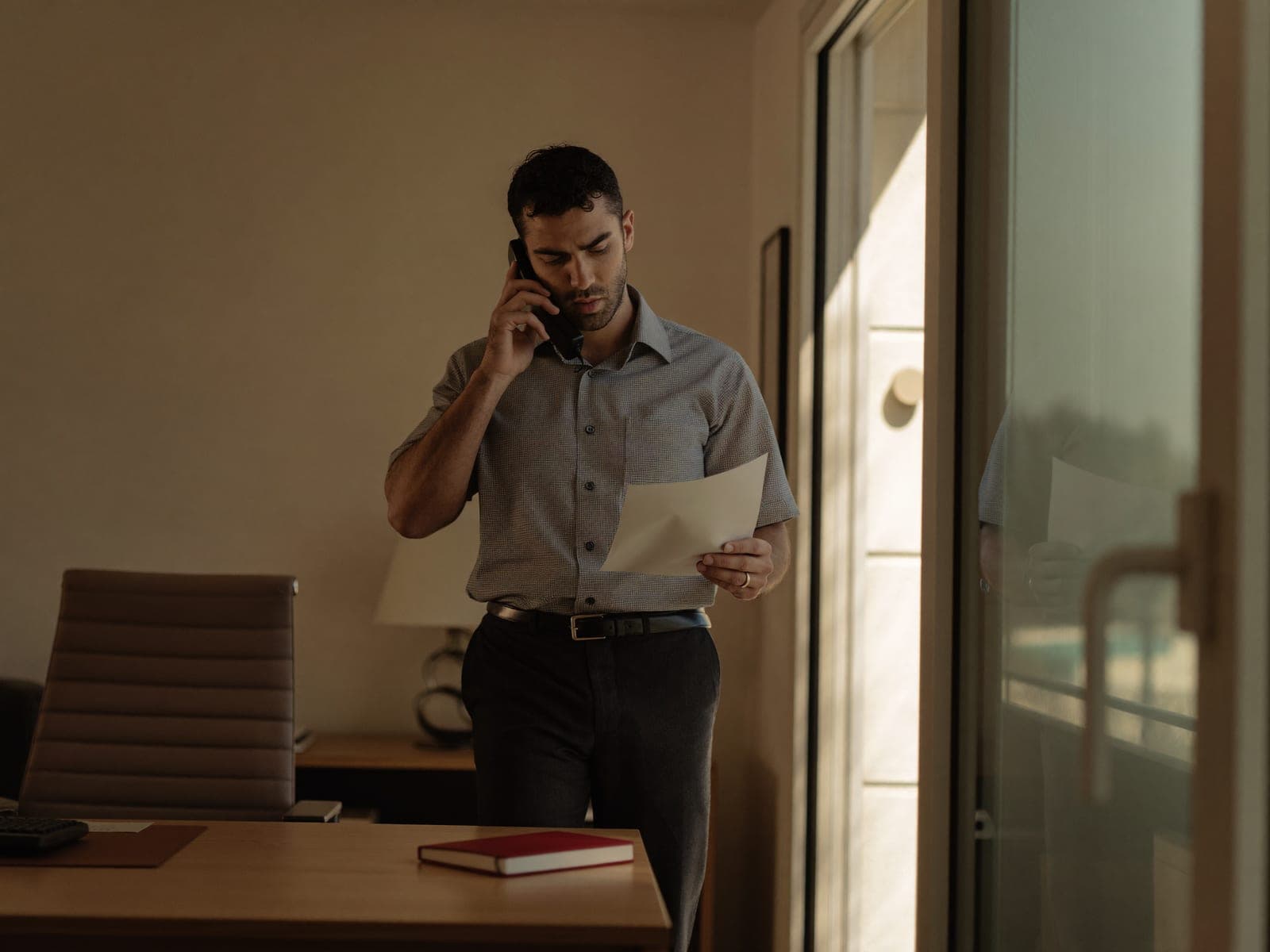 סוכן ביטוח קורא מסמך בשיחת טלפון במשרדו